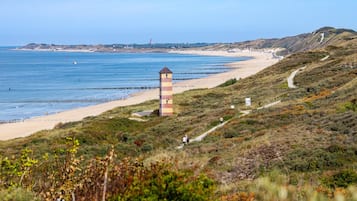 A coastal landscape with a lighthouse, beach, and walking paths.