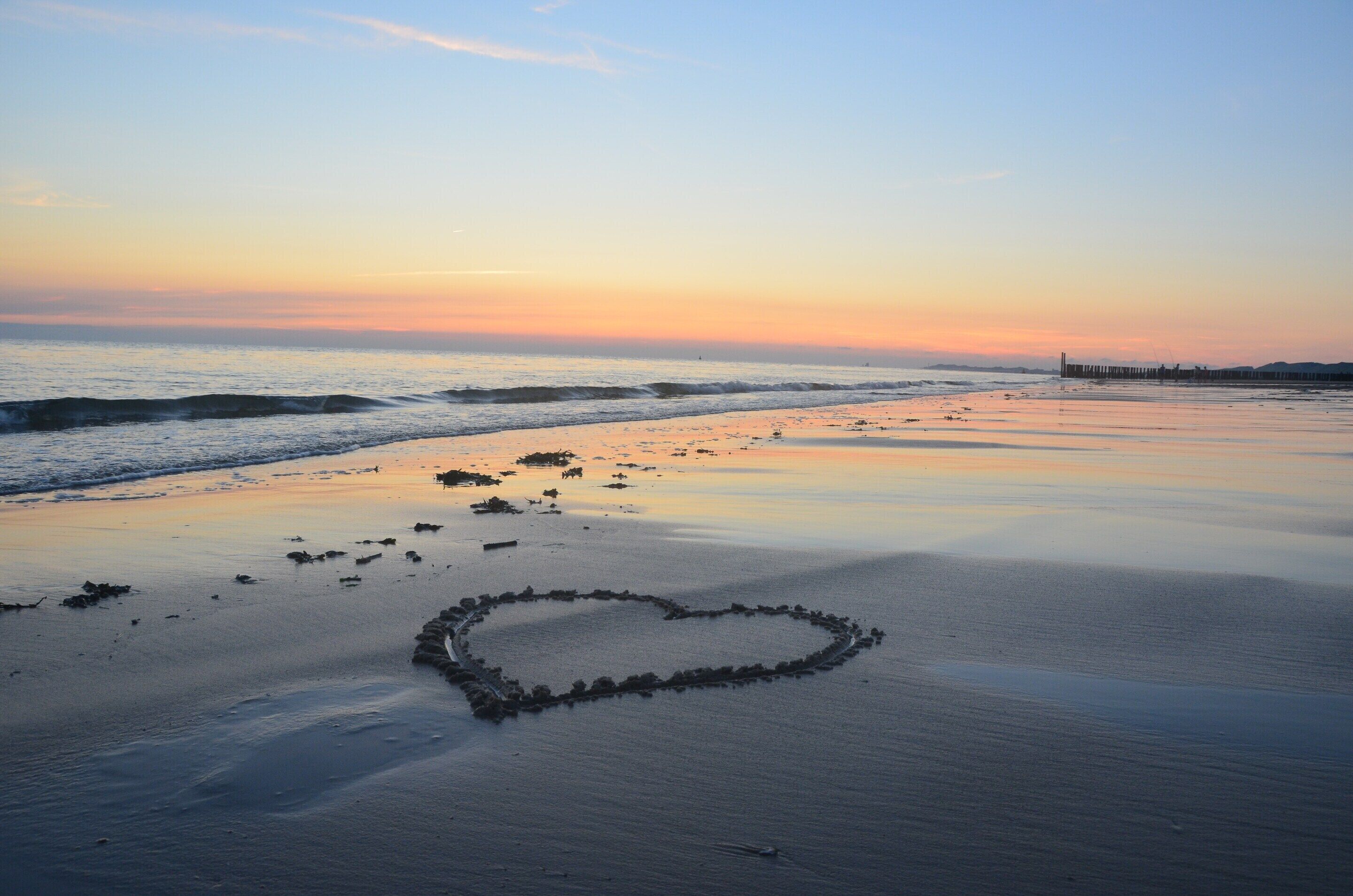 A beach with a heart-shaped rock formation in the sand.