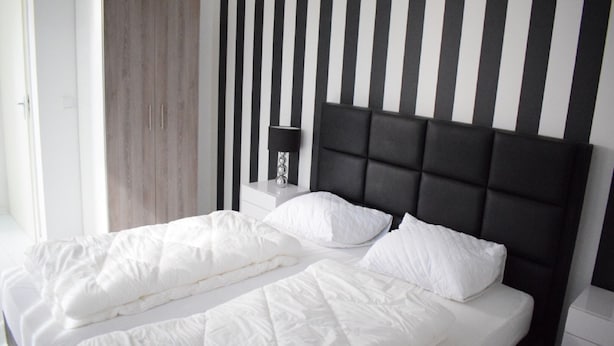 A double bed with white bedding, a dark headboard, and a bedside table with a lamp. - Holiday Home in Harderwijk Near Serene Lake (Zeewolde)