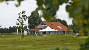 A large building with a red roof and a white marquee on the side. - Holiday Home in Harderwijk Near Serene Lake (Zeewolde)