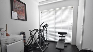 A gym with exercise equipment, a bench, and a window with blinds. - Holiday Home in Harderwijk Near Serene Lake (Zeewolde)
