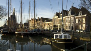 A canal with boats docked, buildings with traditional architecture, and a clear sky. - Lively Cottage near Lake in Schellinkhout (Schellinkhout)