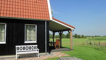 A black house with a red roof, a white bench, and a checkered pavement.