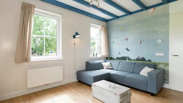 A room with a blue and white color scheme, a sectional sofa, a white coffee table, and a mural of kites on the wall.