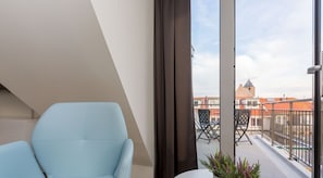 Ein Balkon mit Stuhl, Tisch und Blick auf Gebäude.