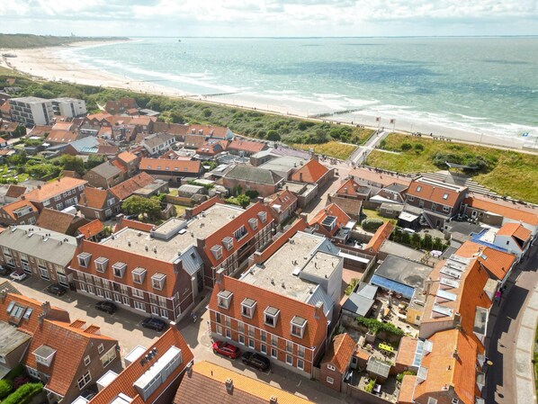 Eine Küstenstadt mit traditionellen Gebäuden mit roten Dächern, einem Strand und einem Steg.