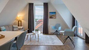 A modern, well-lit room with a dining area, a sofa, and a view of a building through a large window. - Alluring Apartment in Zoutelande near Center & Sea (Zoutelande)