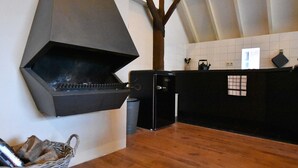 A kitchen with a built-in grill, a wooden table, and a basket of firewood. - Boutique Holiday Home in Nieuwleusen near Forest (Nieuwleusen)