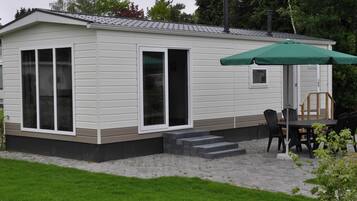 Een kleine, gelijkvloerse stacaravan met een overdekt terras.