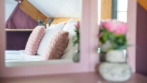 A bedroom with a sloped ceiling, a bed with white linens, and two pink textured pillows. - Holiday Home in Alphen-chaam With Terrace (Alphen)
