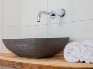 A modern bathroom with a large, dark stone sink, a chrome faucet, and a wooden countertop. - Holiday Home in Koudekerke Near Seabeach (Koudekerke)