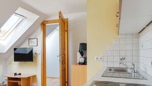 Una cocina moderna con un lavamanos doble, una cafetera y un televisor montado en la pared.