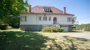 A two-story house with a stone foundation, a balcony, and a front door. - Quaint Holiday Home With Garden (Payzac)