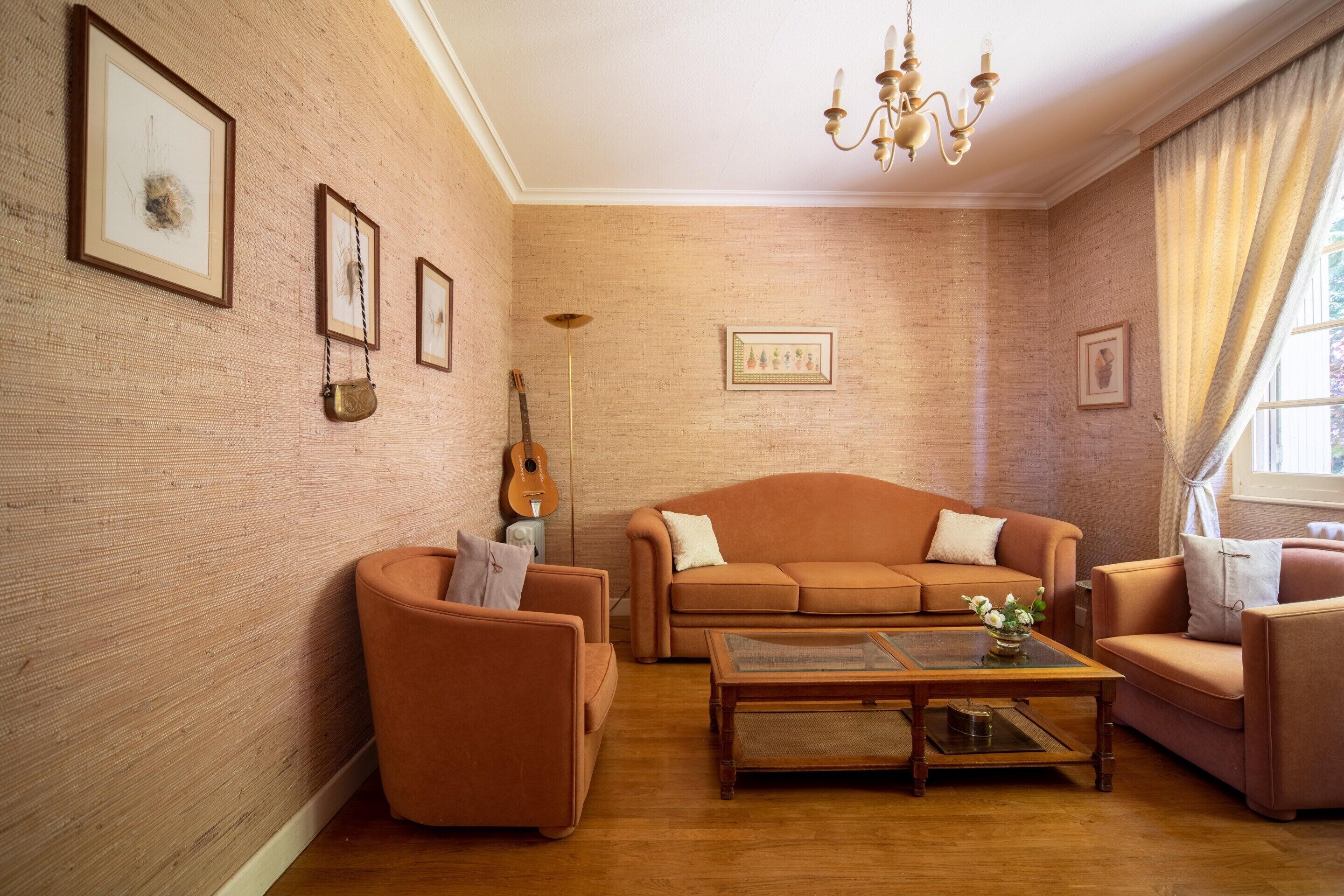 Una sala de estar con pared de ladrillo, un sofá, una mesa de centro y una guitarra.