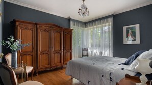 A bedroom with a large bed, wooden wardrobe, and a chandelier. - Quaint Holiday Home With Garden (Payzac)