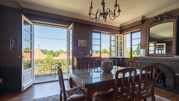 A dining room with a glass table, wooden chairs, a chandelier, and a fireplace. - Quaint Holiday Home With Garden (Payzac)