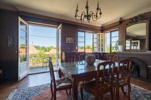 A dining room with a glass table, wooden chairs, a chandelier, and a fireplace. - Quaint Holiday Home With Garden (Payzac)