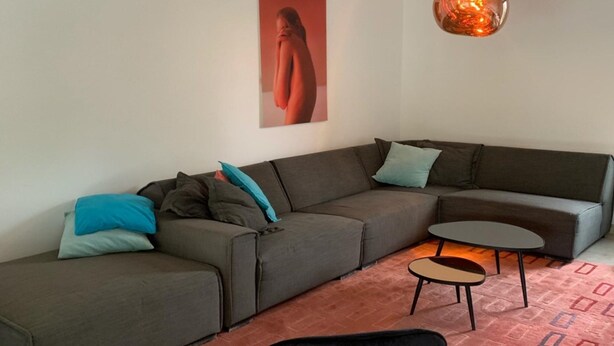 Una sala de estar moderna con un sofá seccional, una silla negra, una mesita y un tapete estampado.