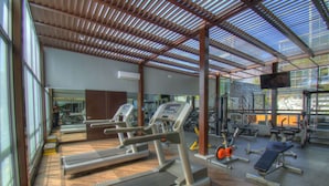 Une salle de sport équipée de tapis de course, d’appareils de musculation et d’un mur recouvert de miroirs.