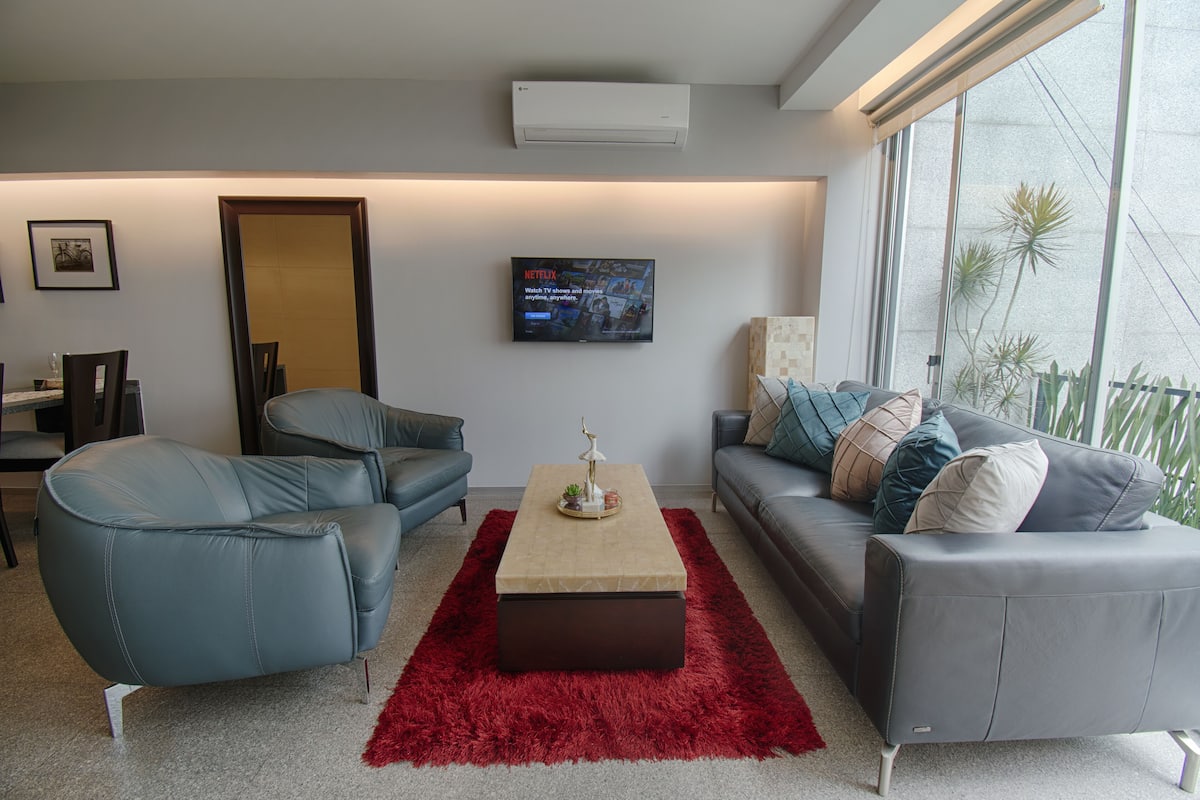 A modern living room with a grey sofa, a red rug, and a coffee table.