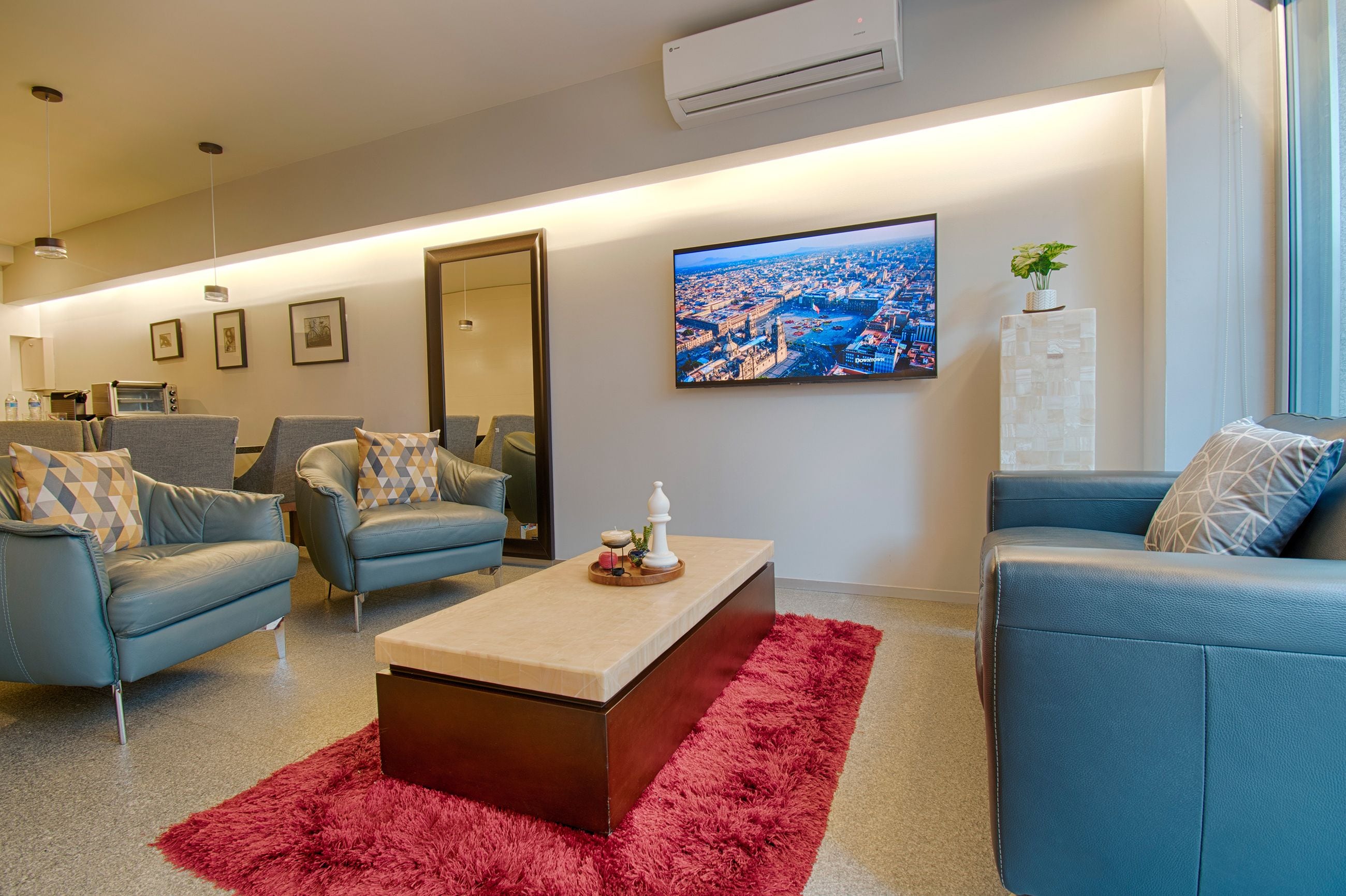 A modern living room with a large flat-screen TV, two sofas, a coffee table, and a red rug.