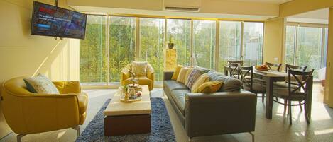 A modern living room with a sofa, armchairs, a coffee table, and a TV mounted on the wall.