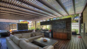 Une terrasse extérieure avec un canapé, une table à manger et un espace barbecue.