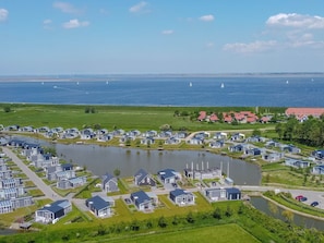 A coastal residential area with modern houses, a lake, and sailboats on the water. - Modern, High-quality Chalet With Wifi Near the Oosterschelde (Wemeldinge)
