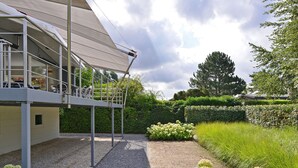 Un espace extérieur abrité, doté d’un chemin de gravier, de buissons d’hortensias blancs et d’une structure métallique.