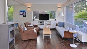 Un salon moderne doté d’une cheminée, d’un téléviseur et d’un balcon aménagé avec du mobilier d’extérieur.