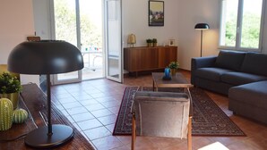 Un saló amb un sofà, una taula, una làmpada i una vista per una porta de vidre.