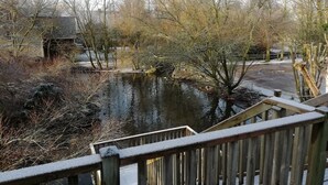 A wooden bridge over a pond with trees and a building in the background. - Quend-plage Apartment With Pool (Quend)