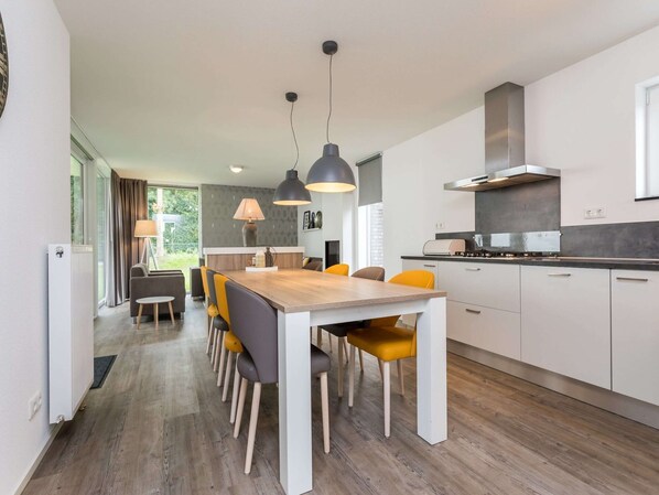 A modern kitchen with a central island, white cabinets, and a stainless steel range hood.