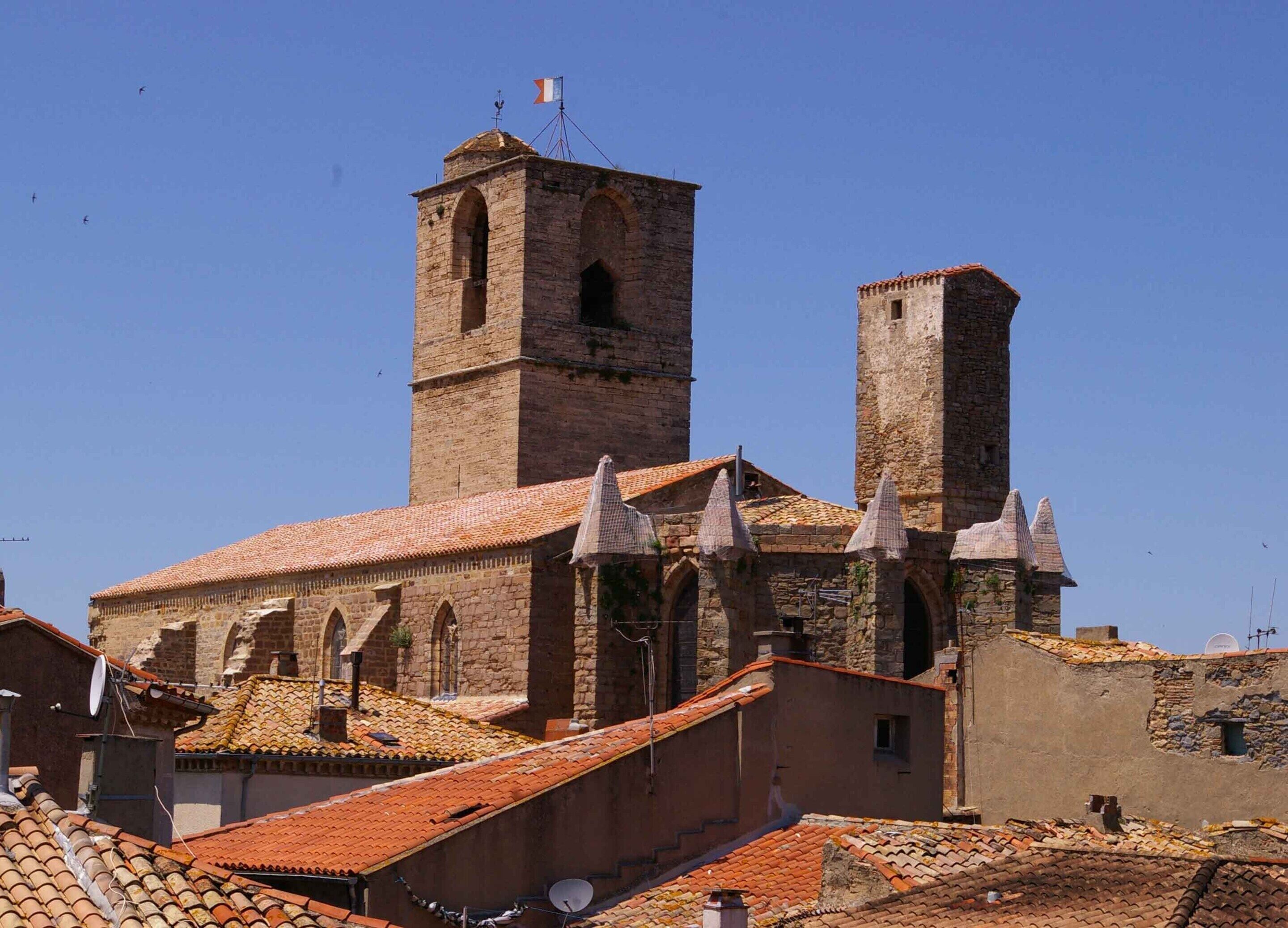 Um edifício histórico com uma torre imponente, janelas em arco e telhado em telhas.