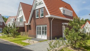 Een modern huis met twee verdiepingen, een rode pannendak, grote ramen en een verzorgd gazon.