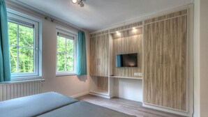 Een moderne slaapkamer met een groot bed, een ingebouwde televisie en houten lambrisering.