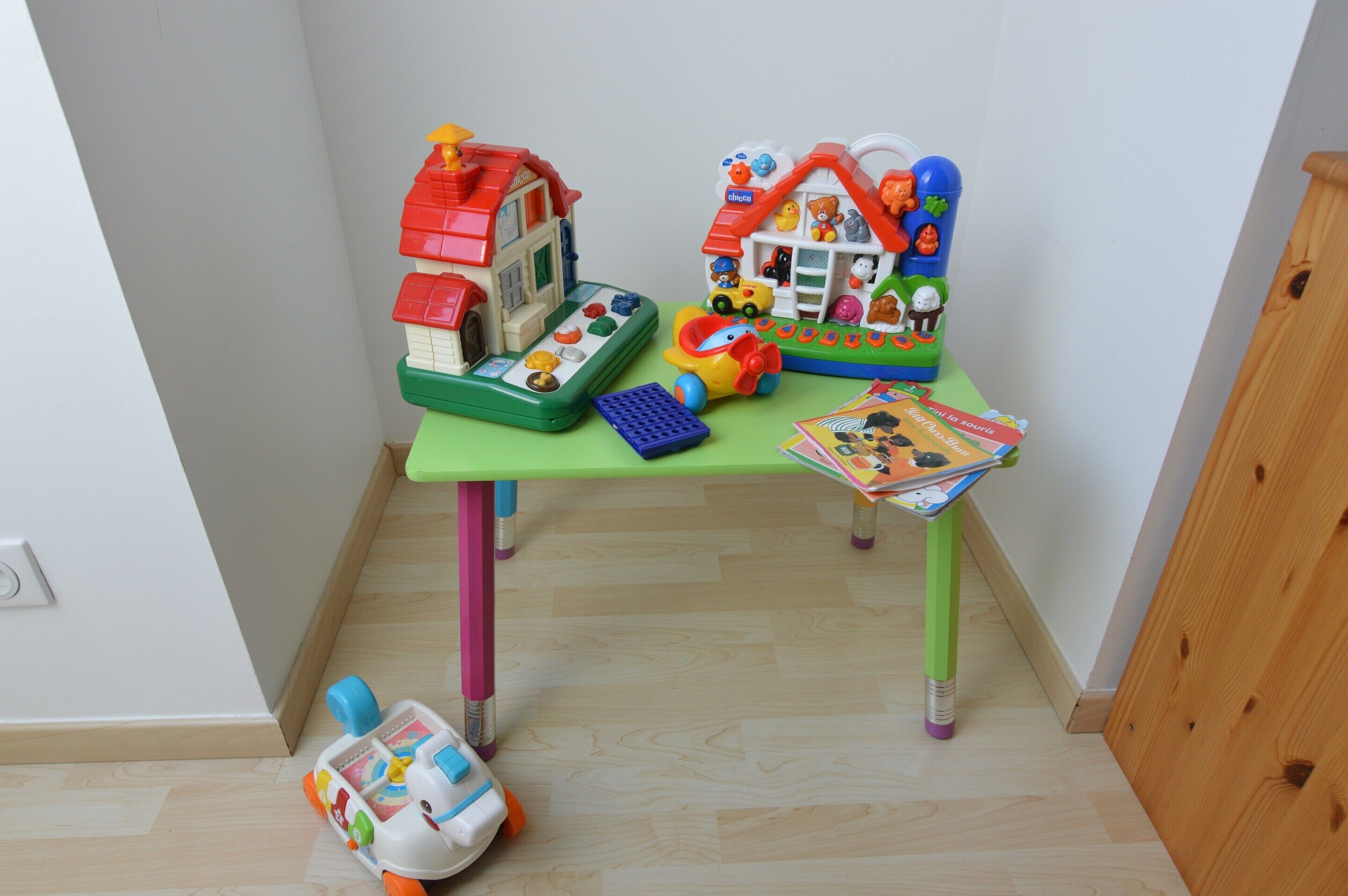 Un pequeño espacio de juegos con una caja registradora de juguete, un coche de juguete y una casita de juguete.