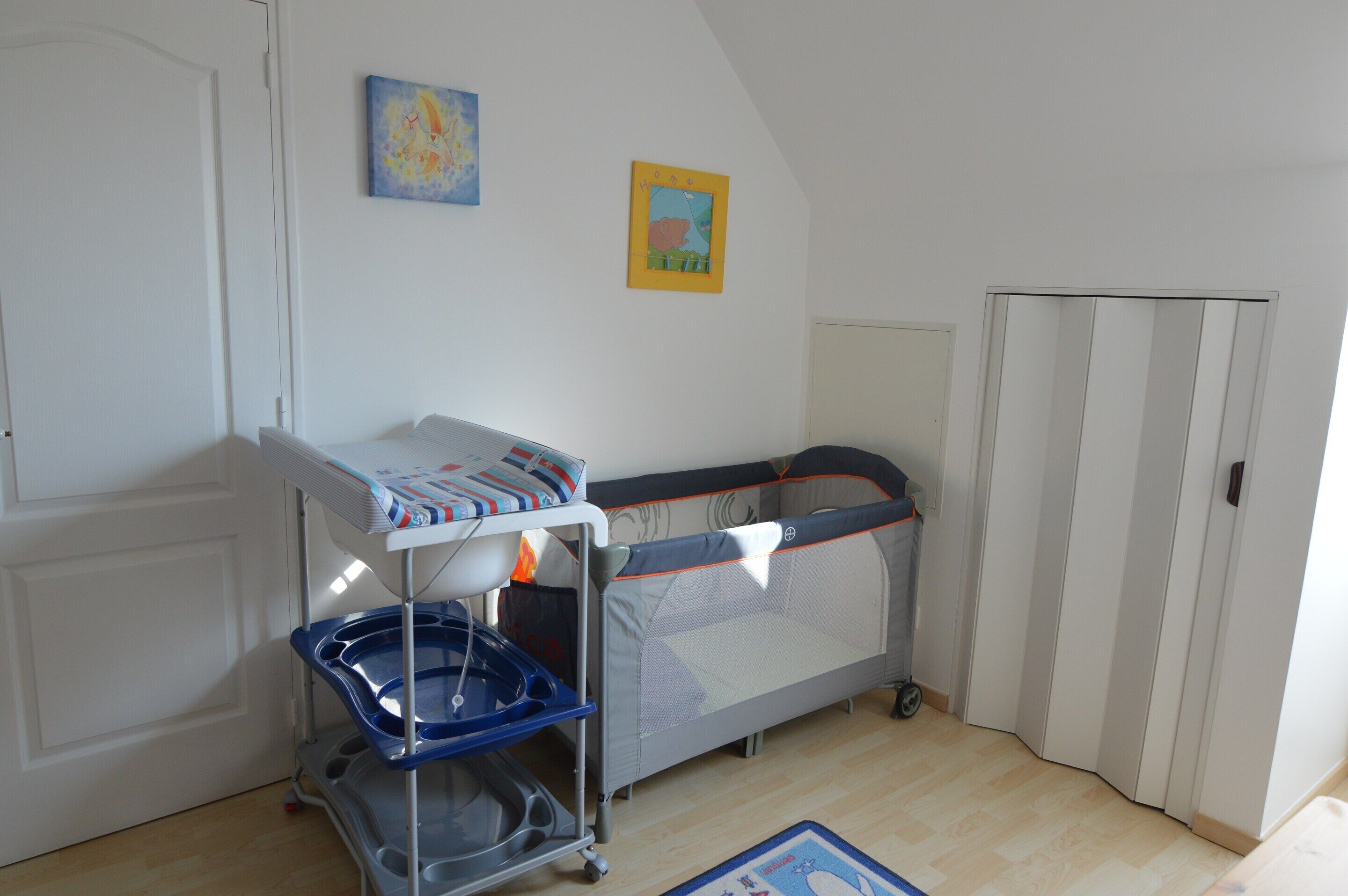 A room with a crib, a changing table, and a door.