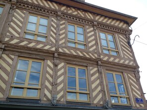 Ein mehrstöckiges Gebäude im traditionellen Baustil, mit einem Fischgrätmuster an der Fassade, zahlreichen Fenstern und einem Straßenschild, das 'Rue de Labbaye' zeigt.