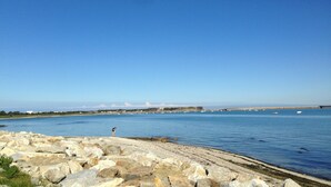 A coastal landscape with a rocky shoreline, calm water, and a clear sky. - Denneville Coastal Escape With Garden (Port-Bail-sur-Mer)