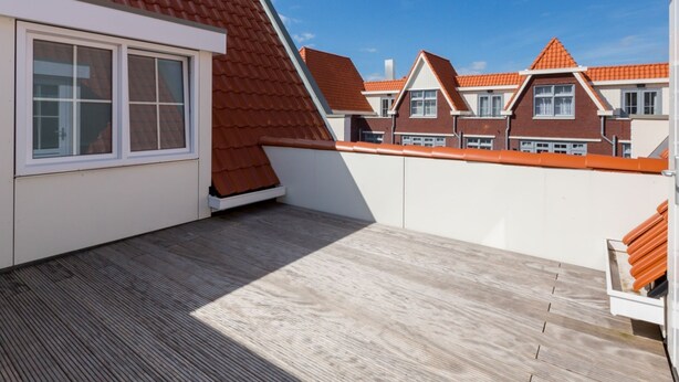 A rooftop terrace with a wooden deck, a red-tiled roof, and a view of neighboring houses. - Luxury Apartment in Koudekerke With Sauna (Koudekerke)