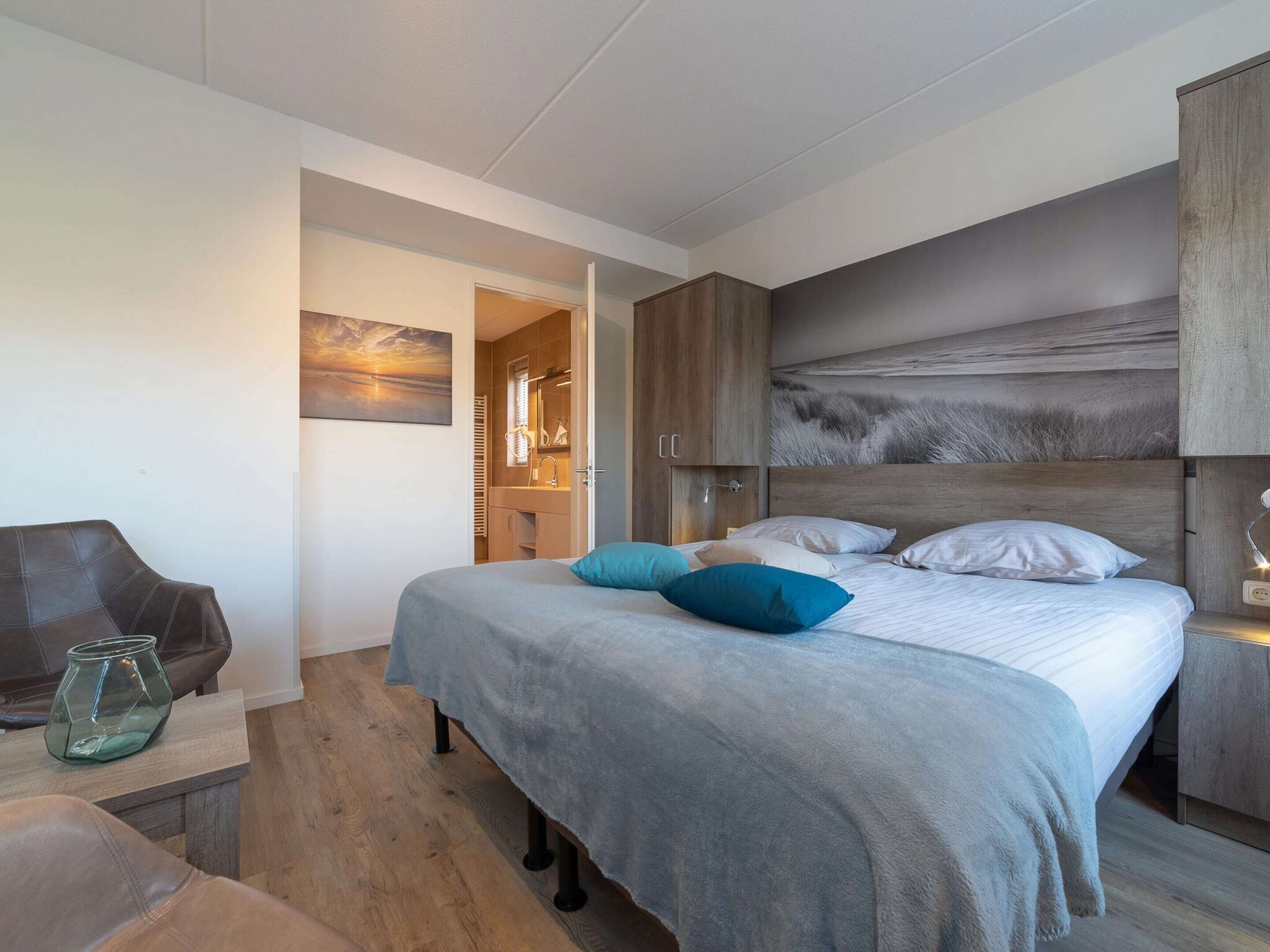 Una camera da letto moderna con un letto grande, una testiera in legno, un comodino e una poltrona.