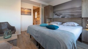 A modern bedroom with a large bed, a wooden headboard, a nightstand, and a chair.