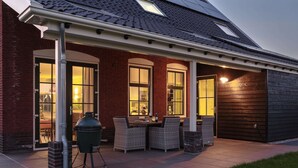 A covered patio area with outdoor furniture and a grill.