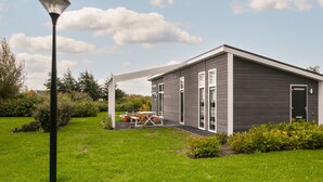 A modern house with a covered patio, a lawn, and a street lamp. - House in Zeeland Near Oosterschelde (Wemeldinge)