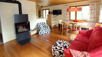 Ein gemütliches Wohnzimmer mit Kamin, Fernseher und Essbereich mit Tisch und Stühlen.
