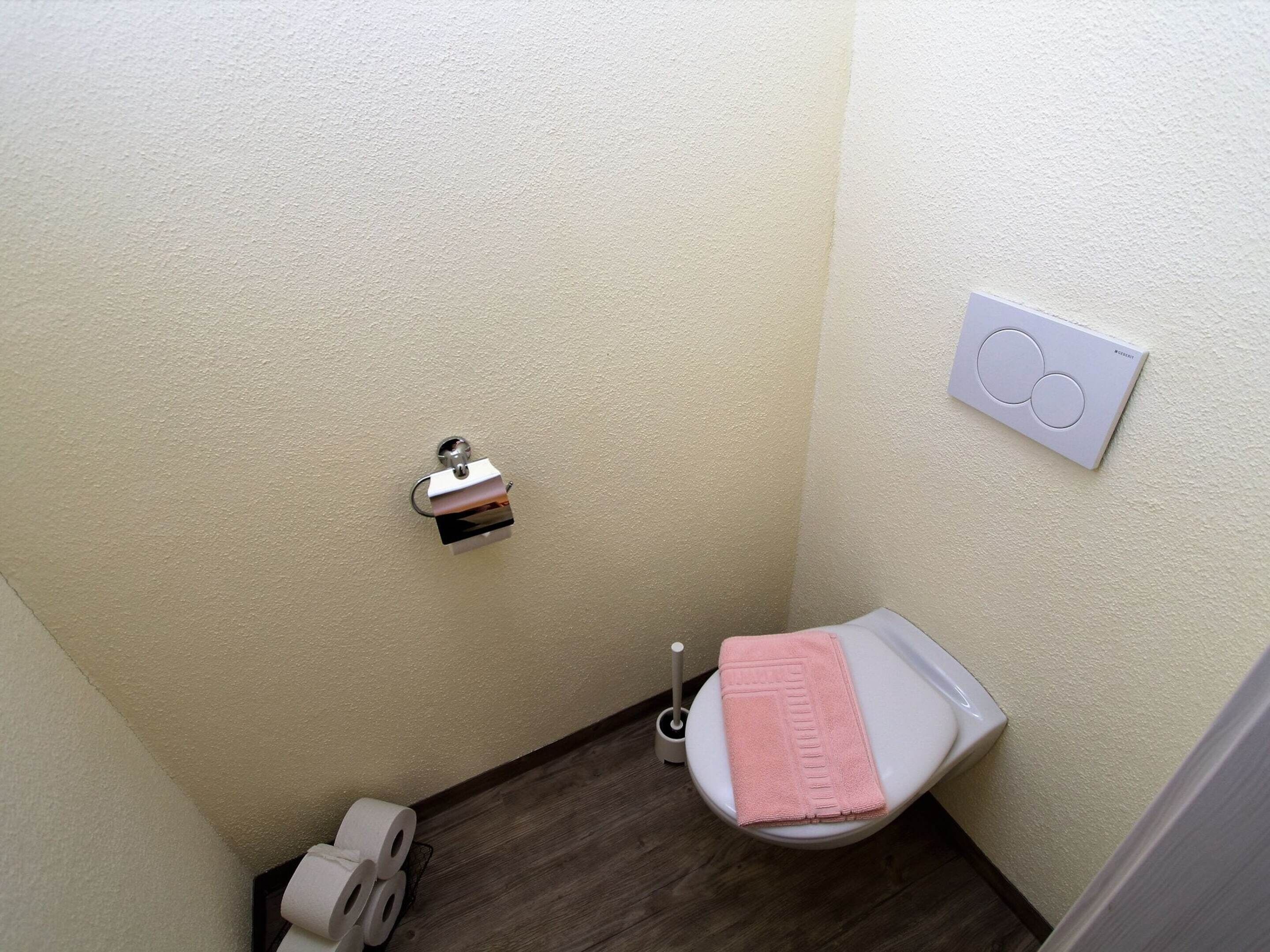A small, narrow bathroom with a toilet, a towel rack, and a toilet paper holder.