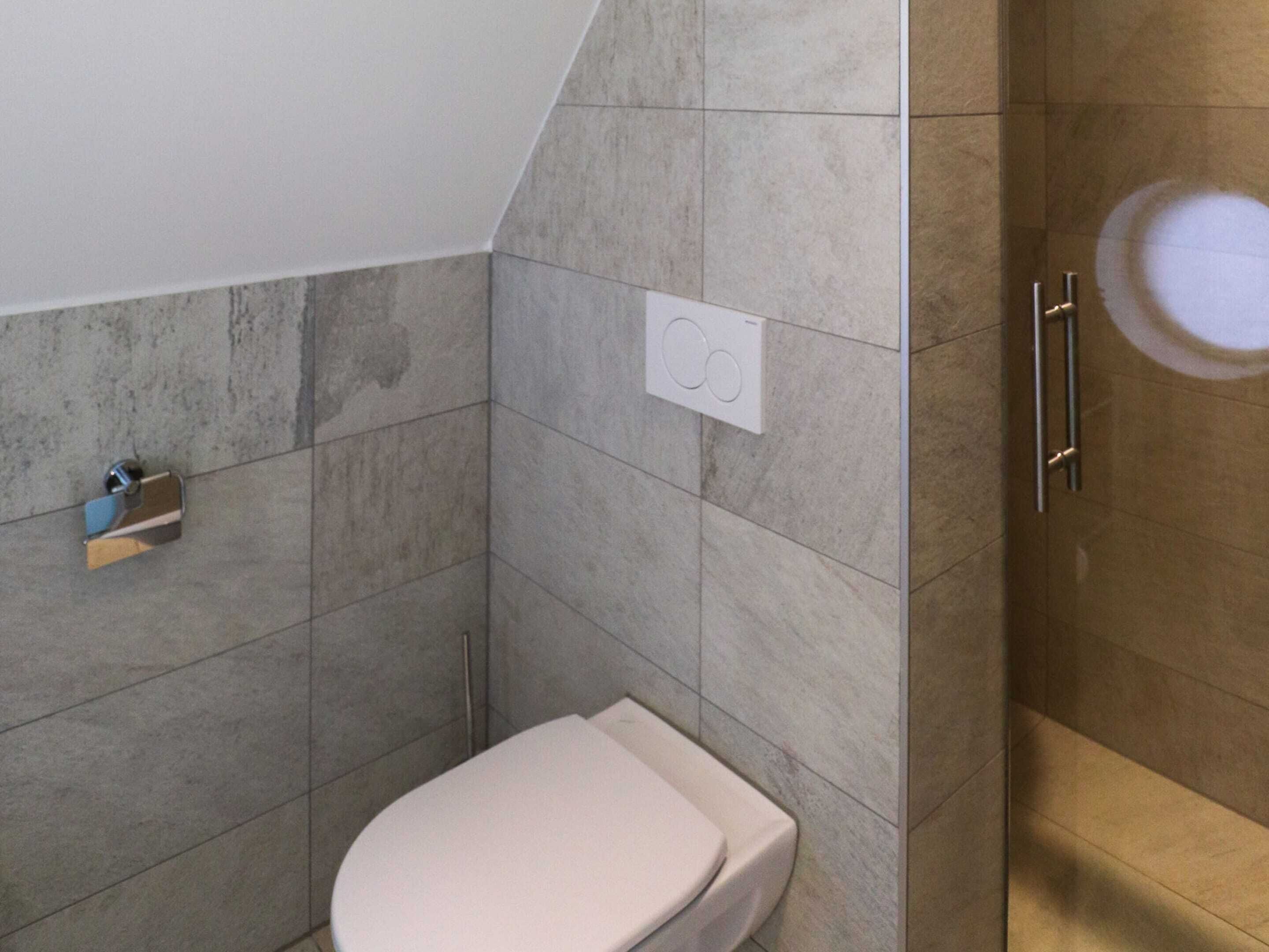 A bathroom with a toilet, a shower, and a towel rack.