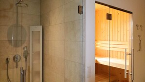 A modern bathroom with a glass-enclosed shower, a wooden sauna, and a white cabinet. - Luxury Villa with Sauna & Hot Tub at Lake (Delfstrahuizen)