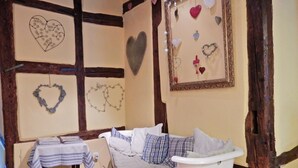 A room with a white sofa, a table with a striped tablecloth, and heart-shaped decorations on the walls. - Apartment in Riquewihr Near Vineyards (Riquewihr)